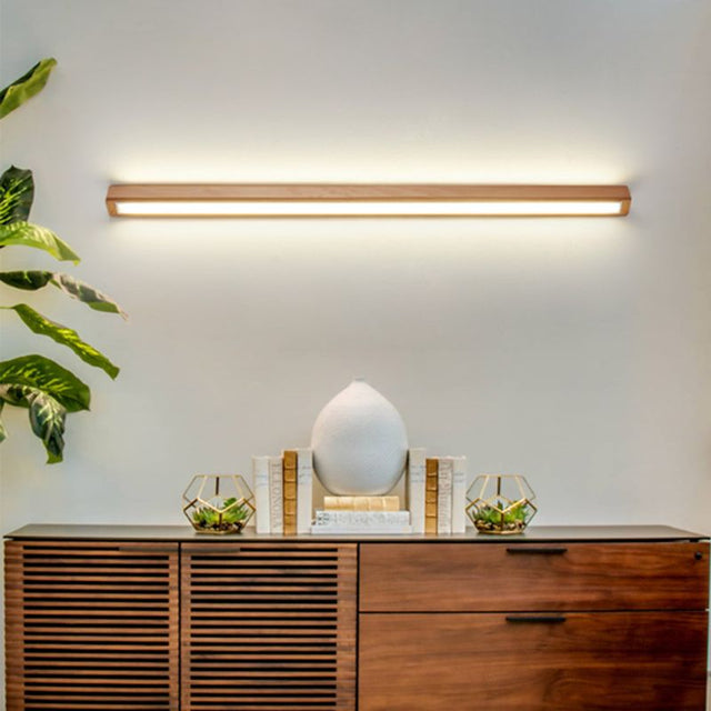 Muto wooden linear wall lamp installed and lit above a sideboard
