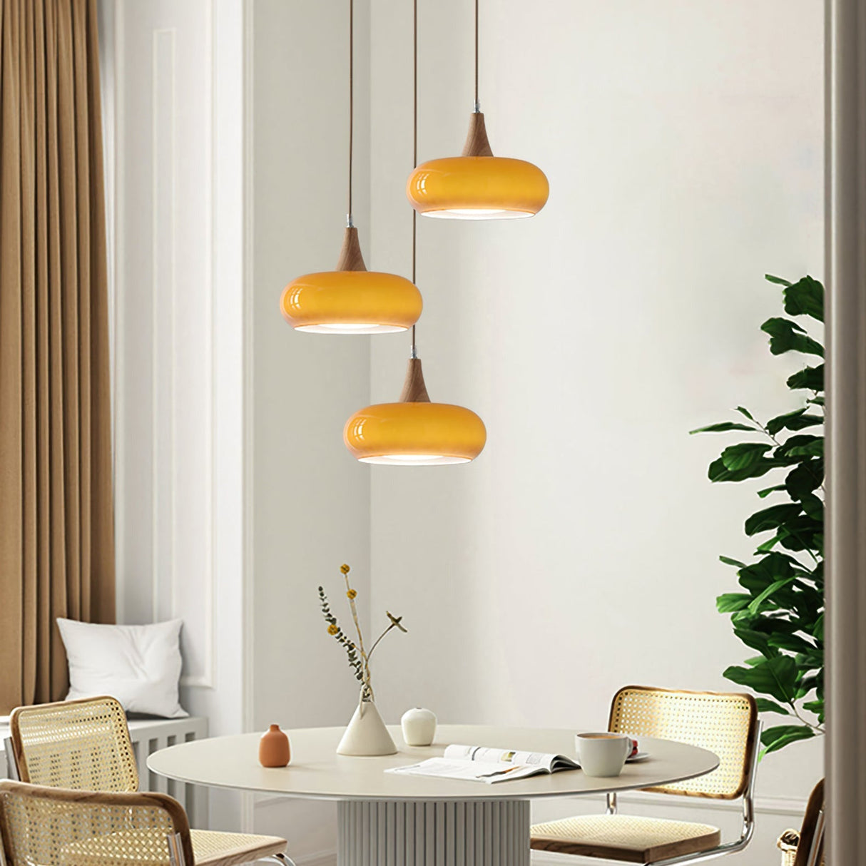 Charlotte amber glass wood pendant light installed and lit above a dining table, 3 heads Orange